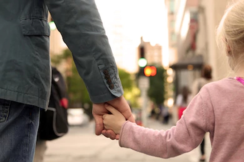 father-holding-child's-hand-crossing-street